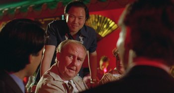 Movie still from “Muriel's Wedding” (1994), directed by P.J. Hogan – A man sitting in front of another man in front of another man; Close Up shot, Over the shoulder angle