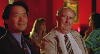 Movie still from “Muriel's Wedding” (1994), directed by P.J. Hogan – A man in a suit and tie next to another man in a suit and tie; Close Up shot, Low angle