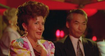 Movie still from “Muriel's Wedding” (1994), directed by P.J. Hogan – An older woman and a younger man are posing for a picture; Close Up shot, Low angle