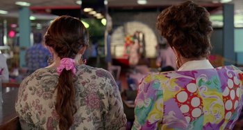 Movie still from “Muriel's Wedding” (1994), directed by P.J. Hogan – Two women in floral shirts are looking at each other; Close Up shot, Over the shoulder angle