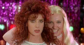 Movie still from “Muriel's Wedding” (1994), directed by P.J. Hogan – Two beautiful women posing for a picture in front of a purple background; Close Up shot, Low angle