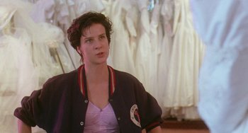 Movie still from “Muriel's Wedding” (1994), directed by P.J. Hogan – A woman is standing in front of a row of dresses; Medium shot, Over the shoulder angle