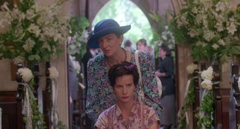 Movie still from “Muriel's Wedding” (1994), directed by P.J. Hogan – A woman in a blue hat standing next to another woman in a floral dress; Medium shot, High angle