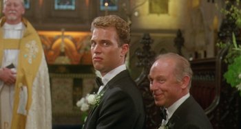 Movie still from “Muriel's Wedding” (1994), directed by P.J. Hogan – A man in a suit standing next to another man in a suit; Close Up shot, Low angle