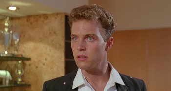 Movie still from “Muriel's Wedding” (1994), directed by P.J. Hogan – A young man with blue eyes wearing a suit and white shirt; Close Up shot, Low angle