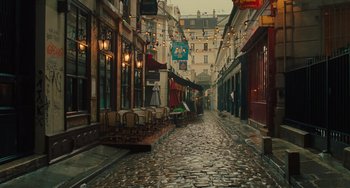 Movie still from “Midnight in Paris” (2011), directed by Woody Allen – An alley way with tables and chairs in it; Extreme Wide shot, High angle