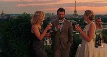 Movie still from “Midnight in Paris” (2011), directed by Woody Allen – A group of people standing around drinking wine; Medium shot, Over the shoulder angle