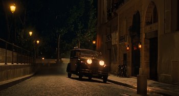 Movie still from “Midnight in Paris” (2011), directed by Woody Allen – An old car parked on the side of the street at night; Extreme Wide shot, Over the shoulder angle