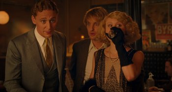 Movie still from “Midnight in Paris” (2011), directed by Woody Allen – A group of people standing next to each other in a room; Medium shot, Over the shoulder angle