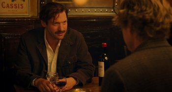 Movie still from “Midnight in Paris” (2011), directed by Woody Allen – A man sitting at a table with a glass of red wine; Medium shot, Over the shoulder angle