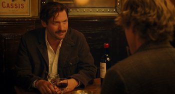 Movie still from “Midnight in Paris” (2011), directed by Woody Allen – A man sitting at a table with a glass of red wine; Medium shot, Over the shoulder angle