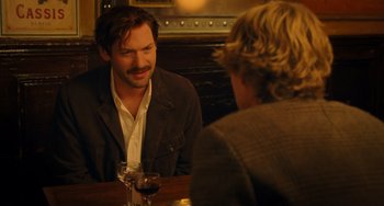 Movie still from “Midnight in Paris” (2011), directed by Woody Allen – A man sitting at a table talking to a woman; Medium shot, Over the shoulder angle