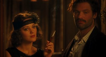 Movie still from “Midnight in Paris” (2011), directed by Woody Allen – A woman holding a cigarette in her hand while a man holds a cigarette in his other hand; Close Up shot, Over the shoulder angle
