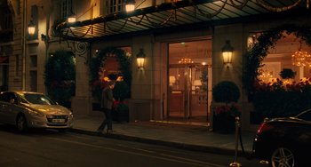 Movie still from “Midnight in Paris” (2011), directed by Woody Allen – A person walking down the sidewalk in front of a building at night; Extreme Wide shot, Low angle