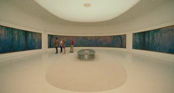 Movie still from “Midnight in Paris” (2011), directed by Woody Allen – A group of people standing in a room with paintings on the wall; Extreme Wide shot, High angle