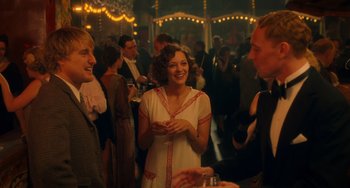 Movie still from “Midnight in Paris” (2011), directed by Woody Allen – A group of people standing in a room with lights in the background; Medium shot, Over the shoulder angle