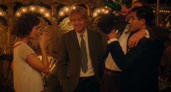 Movie still from “Midnight in Paris” (2011), directed by Woody Allen – A man in a suit and tie standing next to two women; Medium shot, Over the shoulder angle