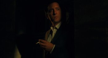 Movie still from “Midnight in Paris” (2011), directed by Woody Allen – A man in a suit and tie smoking a cigarette; Close Up shot, Low angle