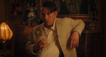 Movie still from “Midnight in Paris” (2011), directed by Woody Allen – A man in a suit holding a glass of wine; Medium shot, Low angle