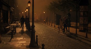 Movie still from “Midnight in Paris” (2011), directed by Woody Allen – People walking down a street at night with street lights; Extreme Wide shot, High angle