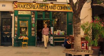 Movie still from “Midnight in Paris” (2011), directed by Woody Allen – A man walking down the sidewalk in front of a store; Wide shot, Low angle