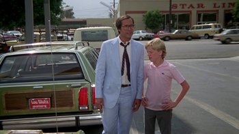 Movie still from “Vacation” (1983), directed by Harold Ramis – A man and a boy standing next to each other in a parking lot; Medium shot, Over the shoulder angle