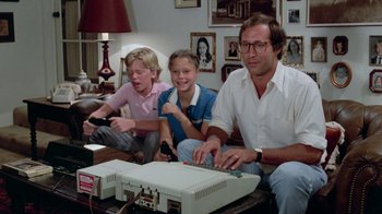 Movie still from “Vacation” (1983), directed by Harold Ramis – A man and two young girls sitting next to each other in front of a computer; Medium shot, High angle
