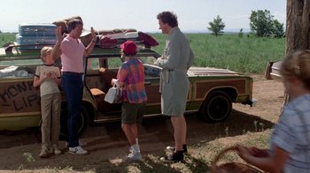 Movie still from “Vacation” (1983), directed by Harold Ramis – A group of people standing next to an old car; Wide shot, Low angle