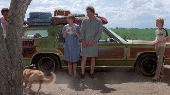 Movie still from “Vacation” (1983), directed by Harold Ramis – A man and a woman standing in front of a car; Wide shot, Low angle