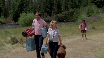 Movie still from “Vacation” (1983), directed by Harold Ramis – A man and a woman walking with their suitcases; Wide shot, Over the shoulder angle