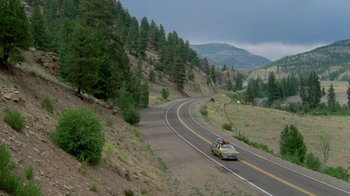 Movie still from “Vacation” (1983), directed by Harold Ramis – A car driving down a road on a cloudy day; Extreme Wide shot, High angle