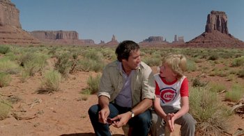 Movie still from “Vacation” (1983), directed by Harold Ramis – A man and a boy sitting on a bench in the middle of the desert; Wide shot, Over the shoulder angle