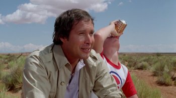 Movie still from “Vacation” (1983), directed by Harold Ramis – A man sitting next to another man holding a cell phone; Close Up shot, Low angle