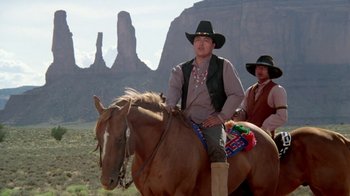 Movie still from “Vacation” (1983), directed by Harold Ramis – A man riding on the back of a brown horse; Wide shot, Over the shoulder angle