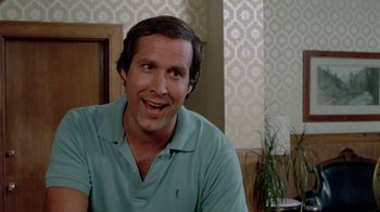 Movie still from “Vacation” (1983), directed by Harold Ramis – A person sitting in front of a window; Close Up shot, Over the shoulder angle