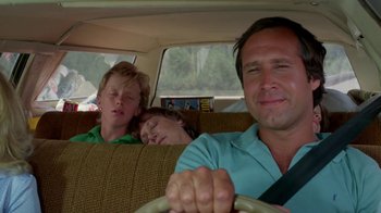 Movie still from “Vacation” (1983), directed by Harold Ramis – A man and two boys sleeping in the backseat of a car; Medium shot, Over the shoulder angle