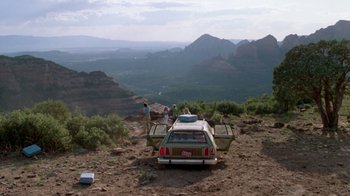 Movie still from “Vacation” (1983), directed by Harold Ramis – Two people standing next to the back end of a car; Extreme Wide shot, High angle