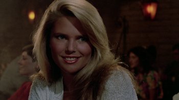 Movie still from “Vacation” (1983), directed by Harold Ramis – A woman with long blonde hair smiling for the camera; Close Up shot, Over the shoulder angle