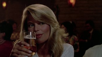 Movie still from “Vacation” (1983), directed by Harold Ramis – A woman holding up a glass of beer in her right hand; Close Up shot, Over the shoulder angle