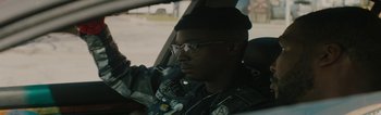 A man in a leather jacket sitting in the driver's seat of a car