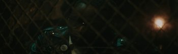 A man with glasses is behind a chain link fence