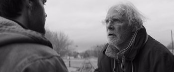 Movie still from “Nebraska” (2013), directed by Alexander Payne – An old man with glasses standing next to train tracks; Close Up shot, Over the shoulder angle