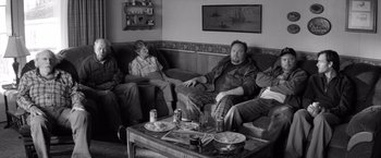 Movie still from “Nebraska” (2013), directed by Alexander Payne – A man sitting on top of a couch next to a table; Wide shot, High angle