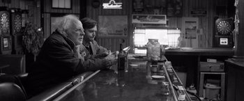 Movie still from “Nebraska” (2013), directed by Alexander Payne – Two men sitting at a bar looking at their cell phones; Medium shot, Over the shoulder angle