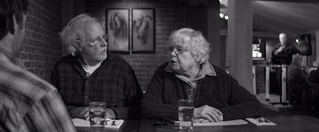 Movie still from “Nebraska” (2013), directed by Alexander Payne – Two older people sitting at a table in front of a painting; Medium shot, Over the shoulder angle