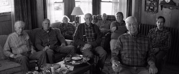 Movie still from “Nebraska” (2013), directed by Alexander Payne – A black and white photo of a group of people sitting in a living room; Wide shot, High angle