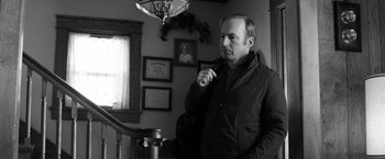Movie still from “Nebraska” (2013), directed by Alexander Payne – Black and white photograph of a man standing in front of a staircase; Medium shot, Over the shoulder angle