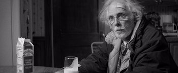 Movie still from “Nebraska” (2013), directed by Alexander Payne – An old man sitting at a table with a glass of water in front of him; Close Up shot, Over the shoulder angle
