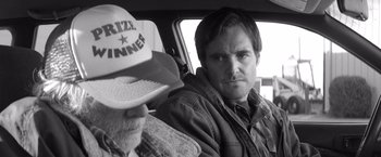 Movie still from “Nebraska” (2013), directed by Alexander Payne – A man sitting in the back seat of a car with another man; Close Up shot, Low angle