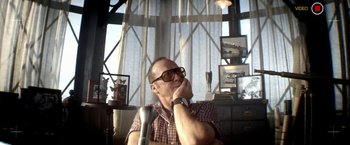 Movie still from “Need for Speed” (2014), directed by Scott Waugh – A man sitting in front of a window with his hand on his chin; Close Up shot, Low angle